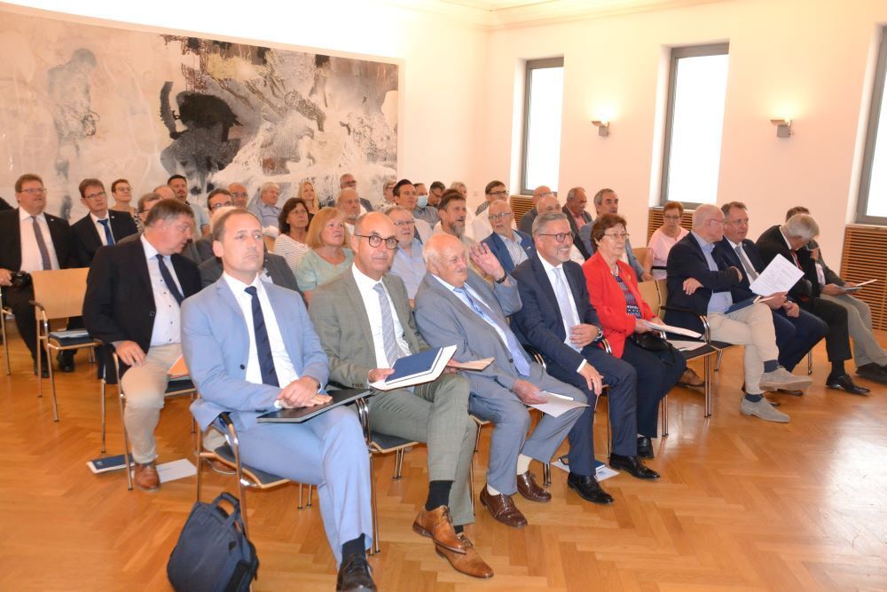 Menschen im Versammlungsraum lauschen einem Vortrag