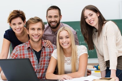 Junge Leute in einem Seminarraum lachen in die Kamera